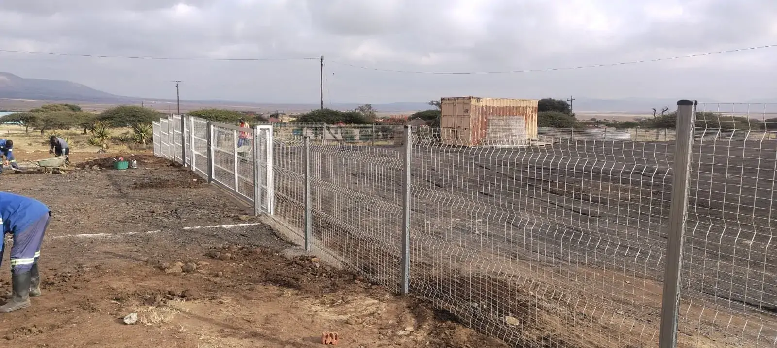 Silver mesh fence and pedestrian gate across a construction site